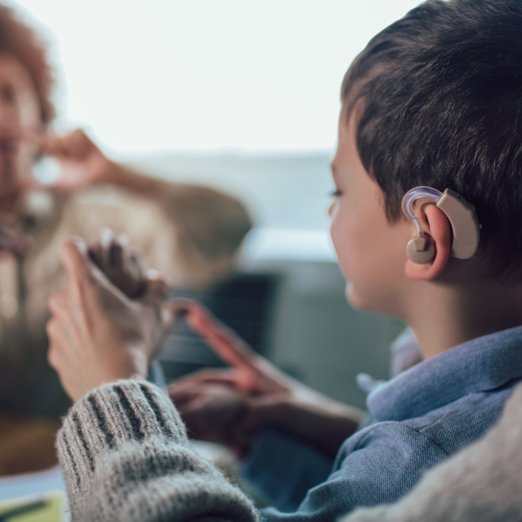 Child with a hearing aid is working with a teacher